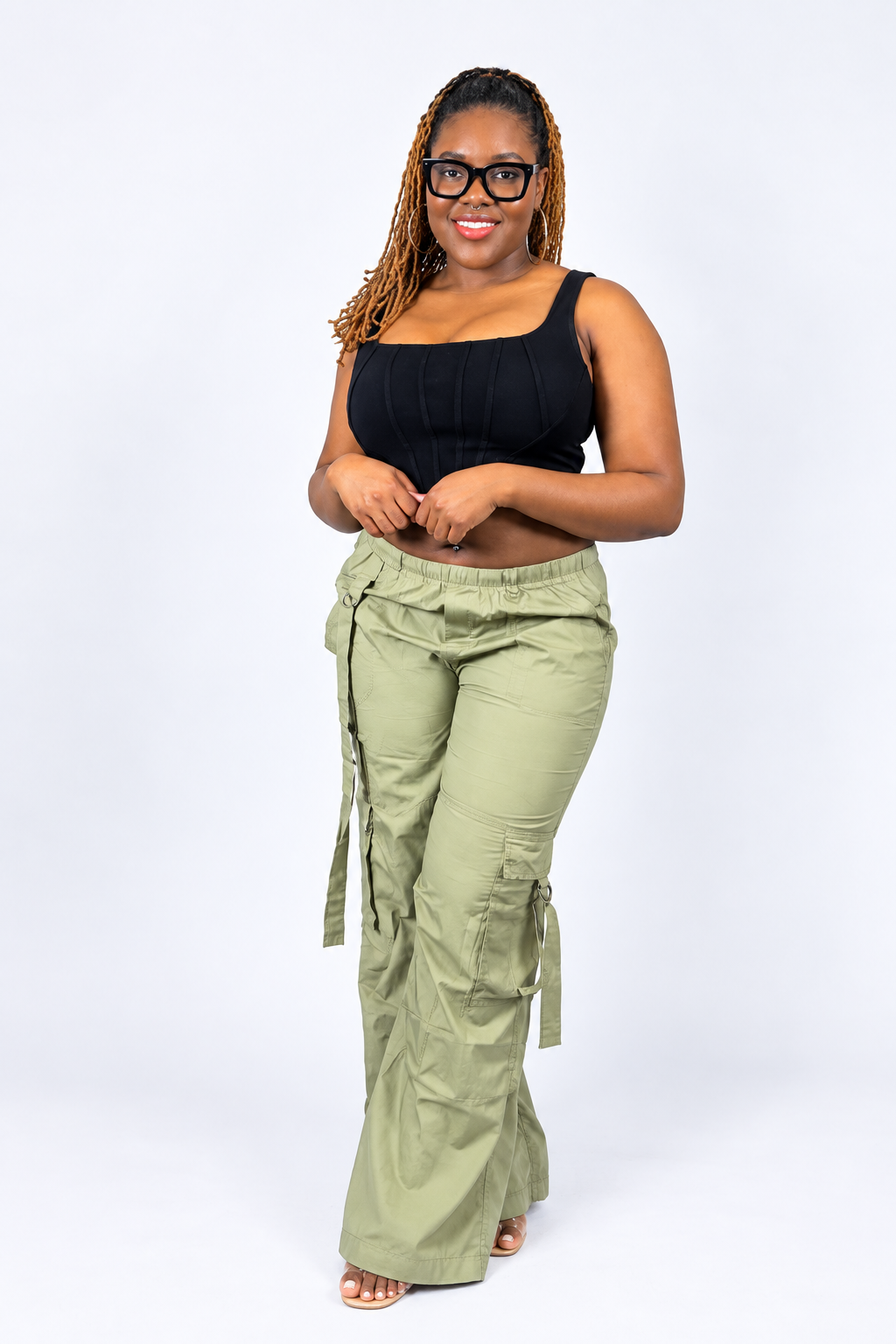 A woman modeling olive green cargo flare pants against a white studio background.