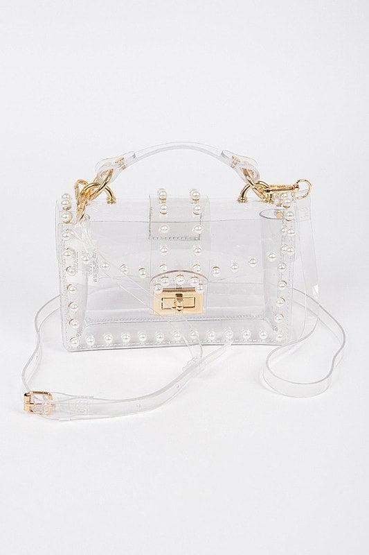 A transparent purse with gold hardware, featuring a shoulder strap and a faux pearl design.